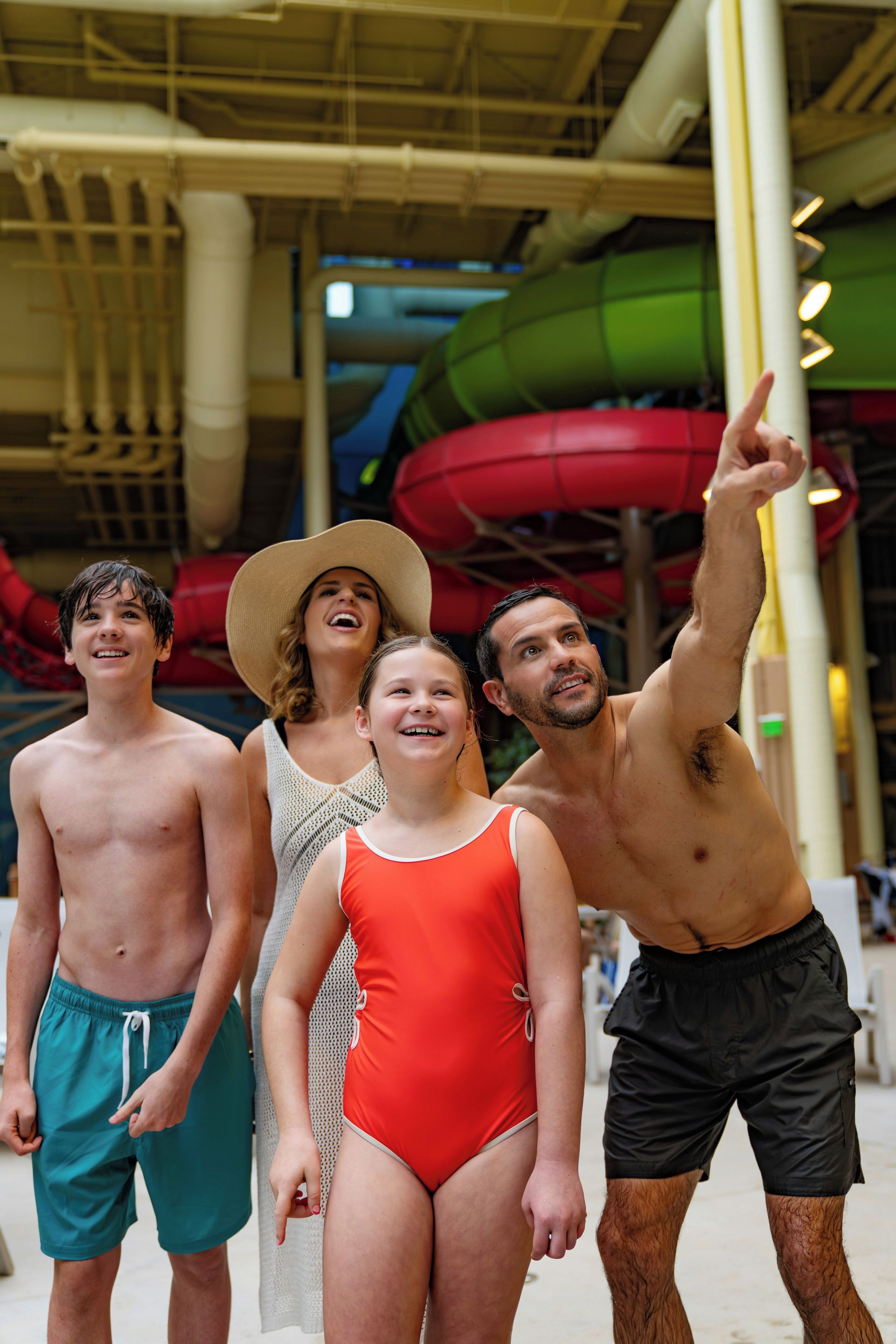 A group of people in swimwear at an indoor water park with slides.