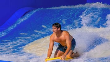 A person surfing on a wave in an indoor facility.