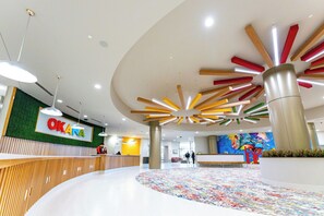 A modern interior with a reception desk, a colorful ceiling design, and a vibrant wall mural. - OKANA Resort & Indoor Waterpark (Oklahoma City)