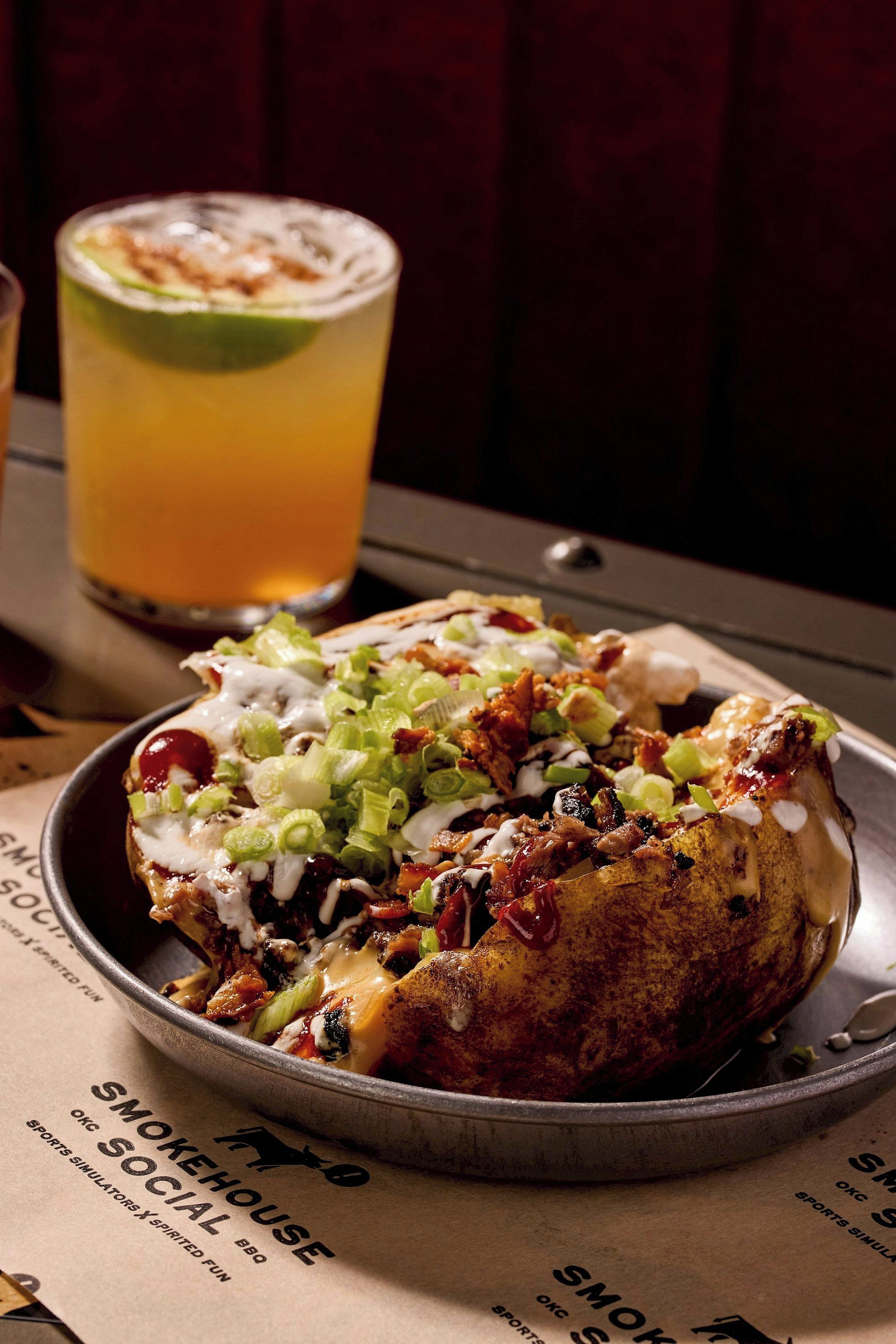 A meal with a tortilla topped with various ingredients, a drink with a lime wedge, and a menu with text.