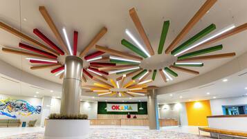 A modern interior with a reception desk, colorful ceiling design, and a patterned carpet.