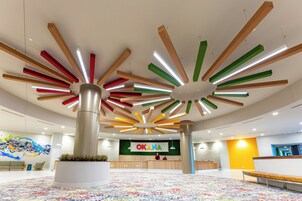 A modern interior with a reception desk, colorful ceiling design, and a patterned carpet.
