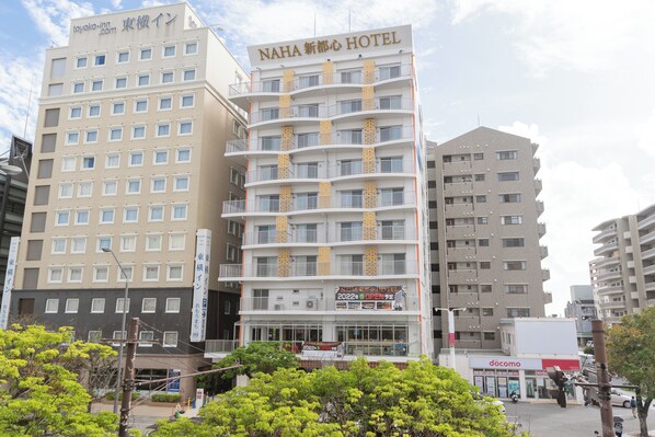 A multi-story hotel with balconies, a sign indicating it's open, and a visible storefront with a sign. - Naha Shintoshin Hotel (Naha)