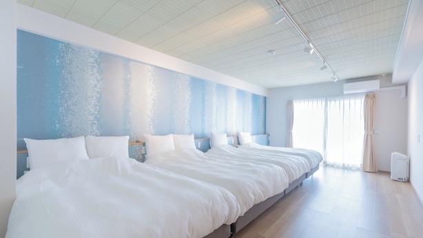 Quarto de hotel moderno e espaçoso, com uma cama grande, janela ampla e iluminação embutida no teto.
