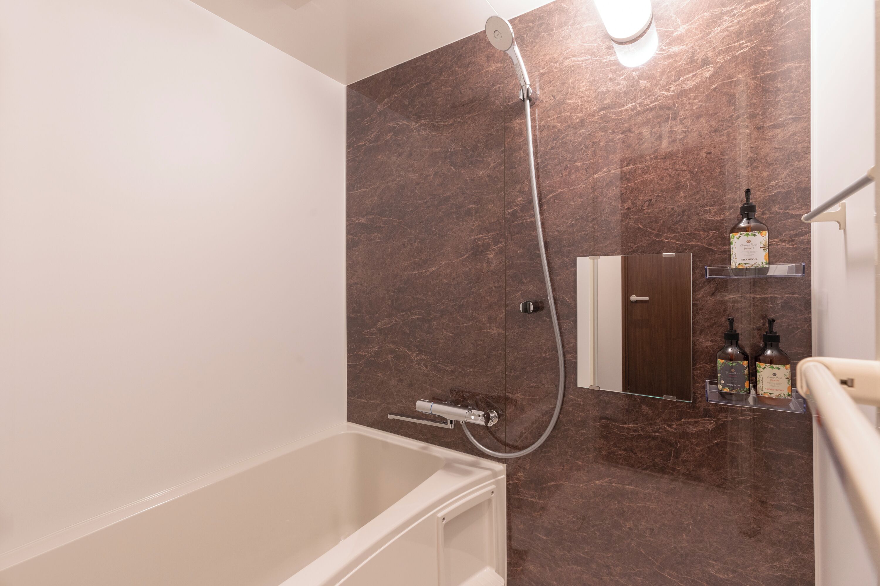 A modern bathroom with a bathtub, a shower, and marble walls.