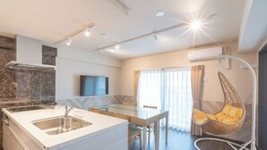 Uma cozinha moderna com mesa de jantar de vidro, uma cadeira suspensa e uma TV fixada na parede.