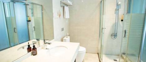A modern bathroom with a large mirror, a sink, a toilet, and a glass-enclosed shower.