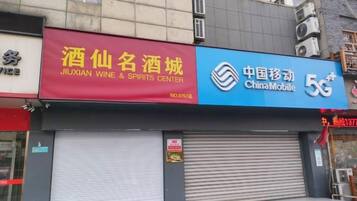 A storefront with a red sign for Jiuxian Wine & Spirits Center and a blue sign for China Mobile 5G.