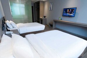 Habitación de hotel con dos camas, televisión, escritorio y vestidor.
