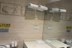 A bathroom with a wet floor sign, towel racks, toilet paper, and a mirror. - Home Inn Baiyun Hotel (Jinhu Suning Yigou Plaza Branch) (Jinhu)