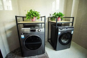 Two stacked washing machines with shelves on top, each holding a potted plant. - Home Inn Baiyun Hotel (Jinhu Suning Yigou Plaza Branch) (Jinhu)
