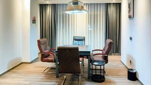 Uma sala de conferência com mesa, cadeiras e uma pequena mesinha lateral.