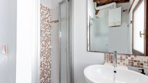 Une salle de bain avec une douche, un lavabo et un miroir.