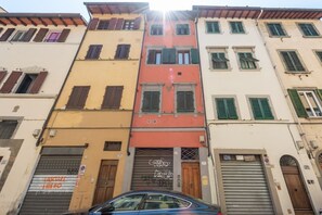 A row of colorful buildings with shutters, a closed garage door, and a car parked in front.