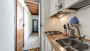 Une cuisine équipée d’un évier en acier inoxydable, d’un plan de travail en bois et d’une cuisinière à gaz.