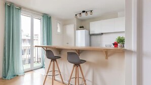 A modern kitchen with a wooden countertop, two bar stools, and a view of the outside through a sliding glass door.