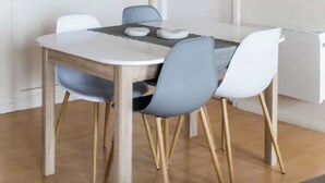 A dining area with a round table, four chairs, and a ceiling light fixture.