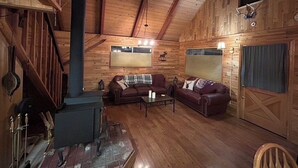 Ein gemütliches Blockhaus-Interieur mit Kamin, Holzwänden und zwei Ledersofas.