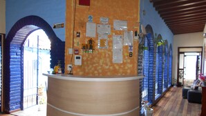 Een receptiezone met een houten balie, een receptie en een muur met verschillende mededelingen en een klein altaartje.