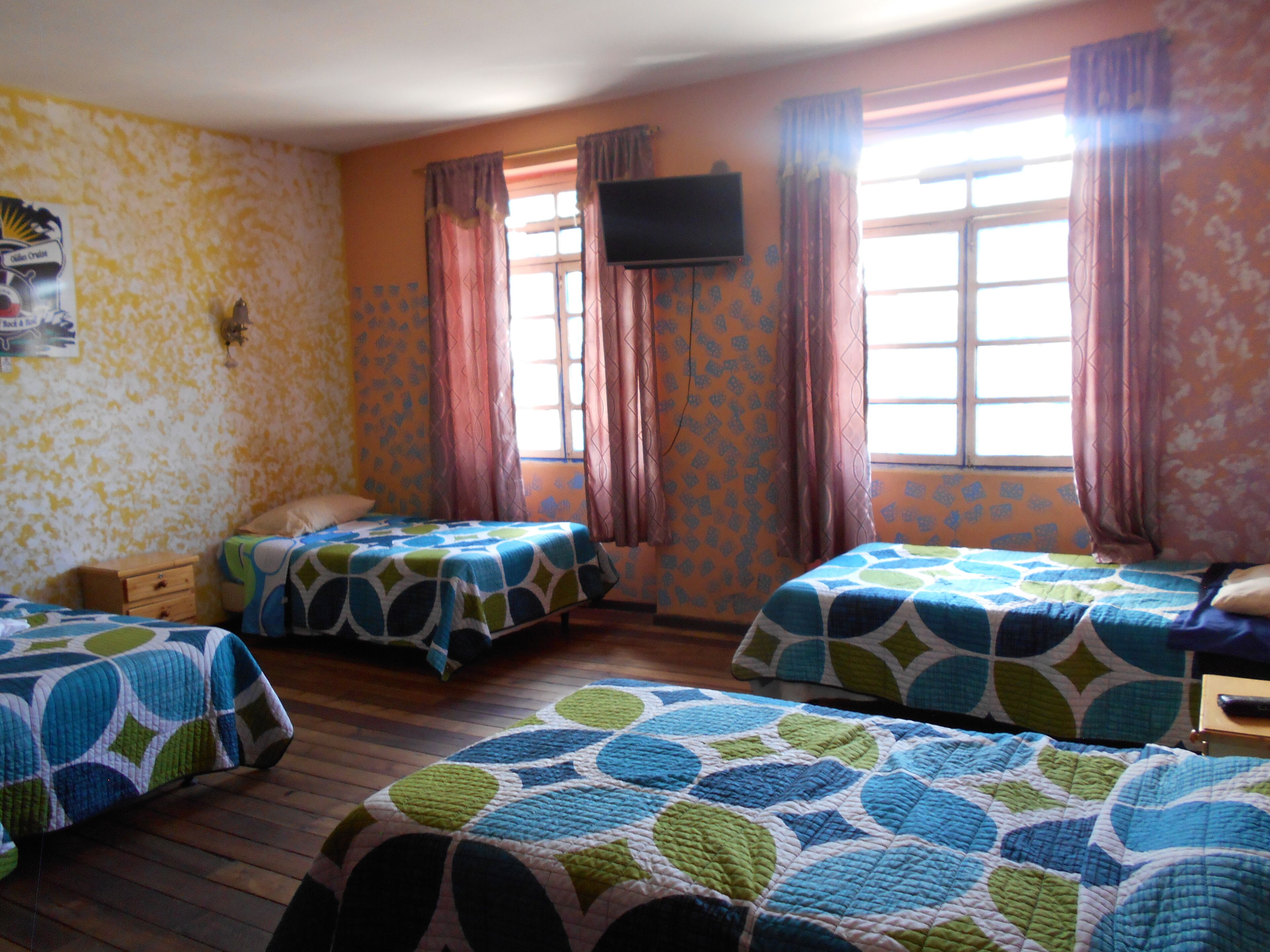 A room with two beds, a TV on the wall, and a window with curtains.