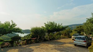 A parking area with two cars, surrounded by greenery and overlooking a body of water. - The Dandy Horizon (Igoumenitsa)