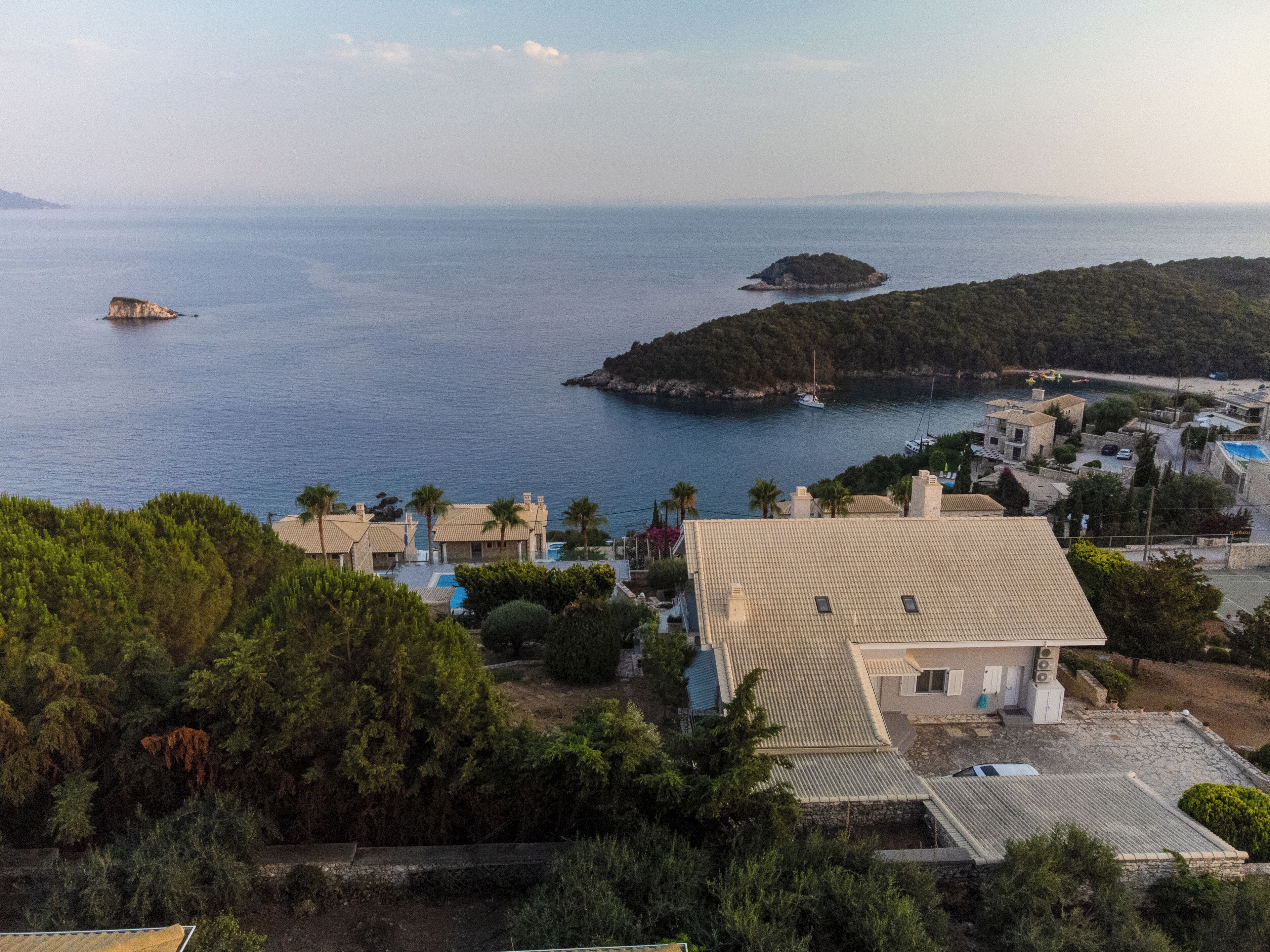 A coastal property with a pool, a small island in the background, and a view of the sea.