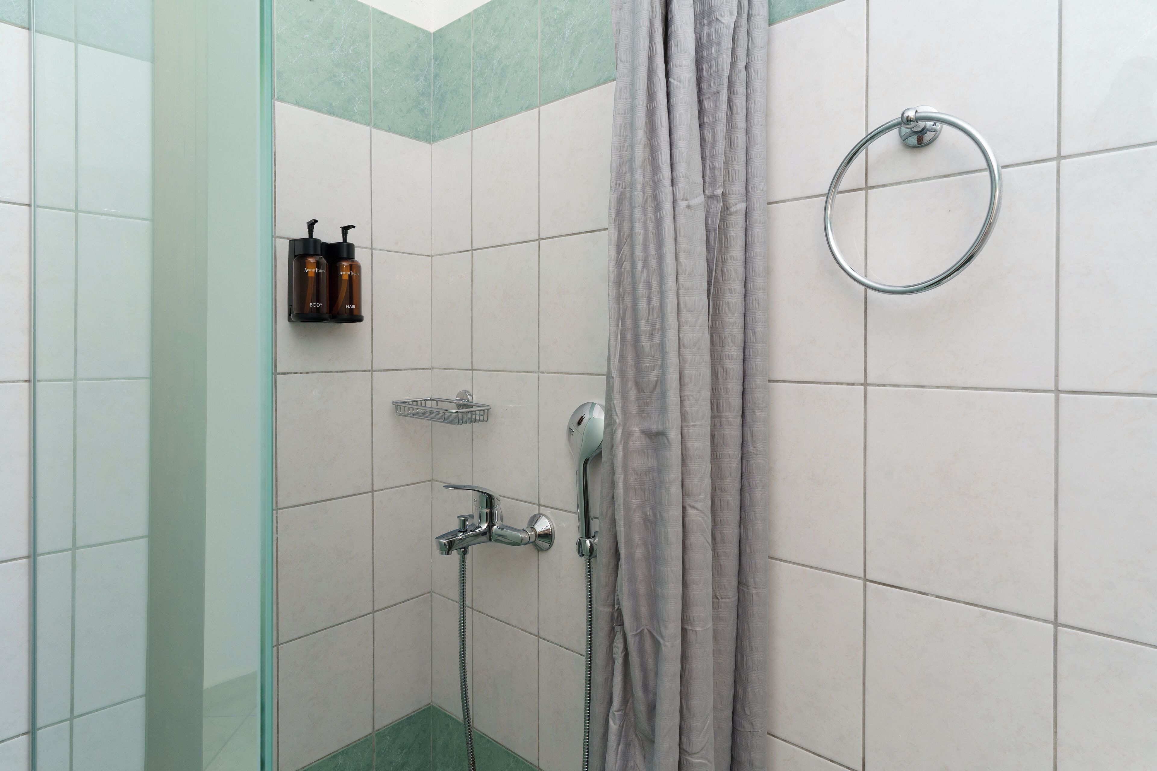 A shower area with a glass door, a towel ring, and a showerhead.