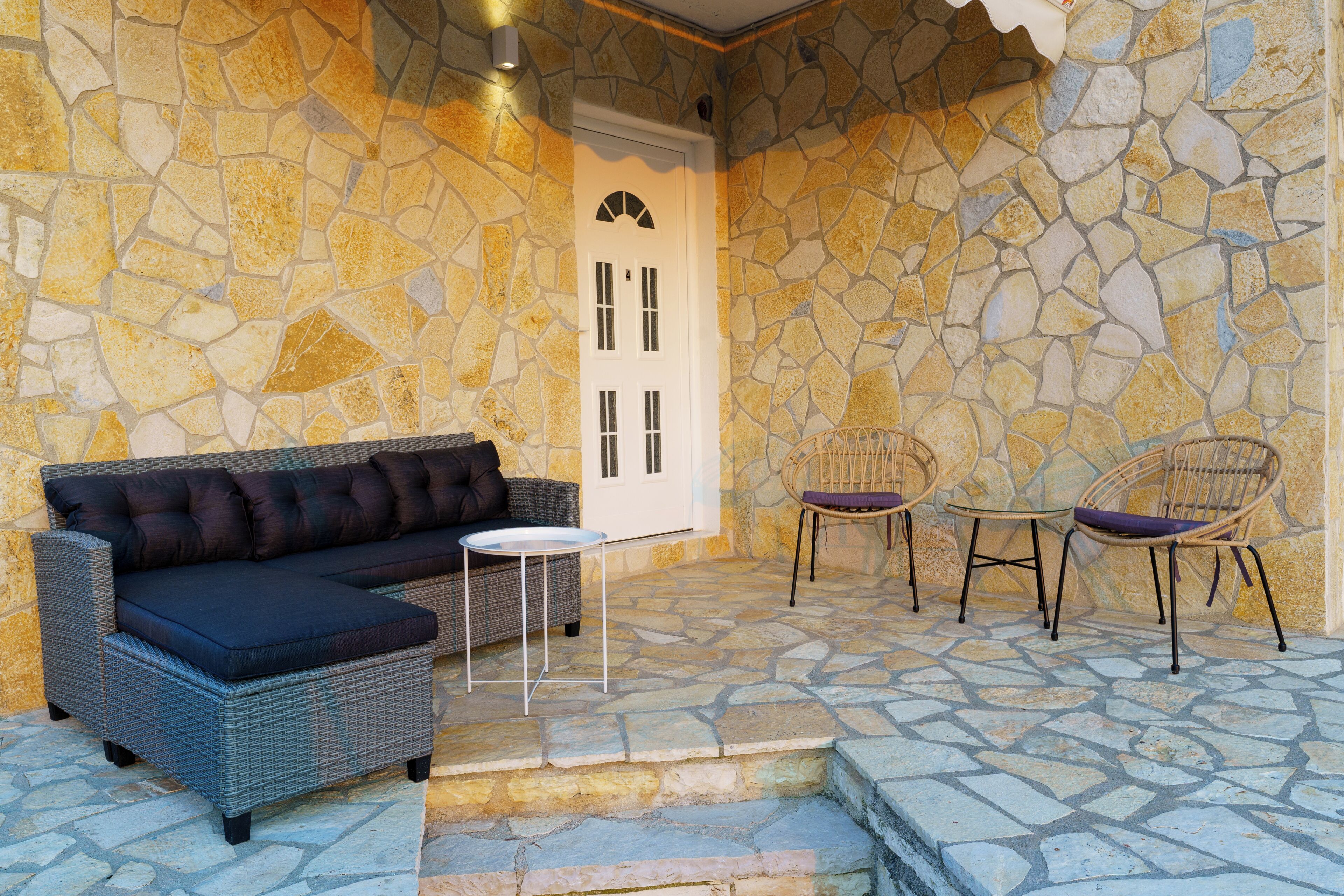 Patio in pietra con un divano, due poltrone e un tavolino.