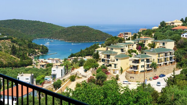 A coastal residential area with multiple two-story buildings, a marina with boats, and a clear view of the sea. - The Dandy Horizon (Igoumenitsa)