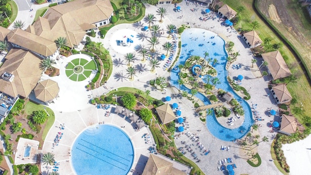 Una vista aerea di un resort con diverse piscine, palme e zone relax.