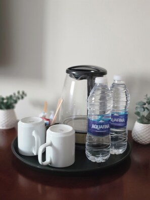 Ein Tisch mit einer Kaffeemaschine, zwei Wasserflaschen und zwei weißen Tassen.