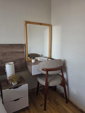 A room with a wooden desk, a chair, a mirror, a small plant, and a white lamp. - Pyramids Tower Inn (Giza)