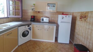 Una cucina compatta con lavatrice, forno a microonde, frigorifero e lavello.