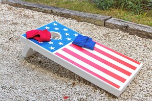 A beach chair with an American flag design, placed on a gravel surface. - Private Beach Access |Sound Views |Elevator (Surf City)