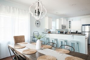 A modern kitchen with white cabinetry, a central island with stools, and a chandelier. - Private Beach Access |Sound Views |Elevator (Surf City)