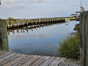A wooden dock extending over calm water with a boat docked on the right. - Private Beach Access |Sound Views |Elevator (Surf City)