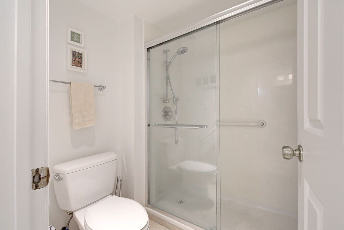 A bathroom with a toilet, a glass shower enclosure, and a towel rack.