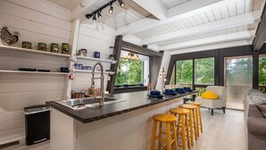 A kitchen with a central island, bar stools, a sink, and shelves with jars. - Country Squire Cabin - private 180 degree mountain views! (Basye)