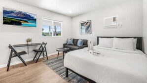 Ein modernes Hotelzimmer mit Bett, Schreibtisch und Sofa. Ein Fenster bietet Blick auf die Stadtlandschaft.