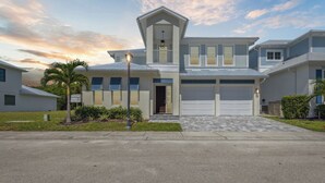 A modern two-story house with a garage, a covered front porch, and a well-maintained lawn. - Tropical Backyard Oasis w/ Pool, Game Room & Outdoor BBQ! 🌞 (Fort Pierce)