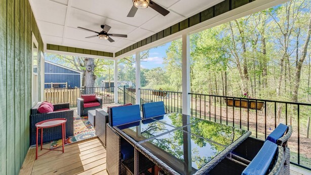 Un espacio al aire libre techado con muebles de mimbre, una mesa de vidrio y ventiladores de techo.