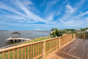 A wooden deck with a gazebo overlooking a lake, surrounded by greenery and houses. - ONHC21D: Soundfront, Private Boat Dock, Sunset Views! (Nags Head)
