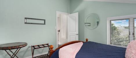 Une chambre à coucher avec un lit, un miroir rond, une petite table et une porte.
