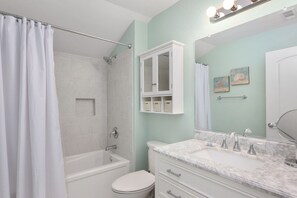 Une salle de bain équipée d’une douche, de toilettes et d’un meuble-lavabo avec un miroir et des placards.