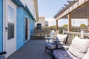 A covered deck with outdoor furniture, a wooden pergola, and a view of neighboring houses.