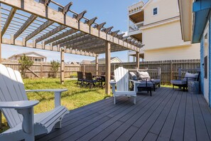 Una terraza de madera con sillas Adirondack y una pérgola.