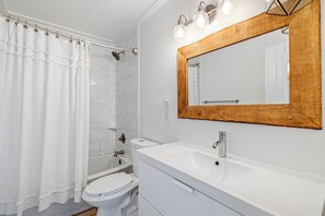 A modern bathroom with a shower, toilet, sink, and vanity.