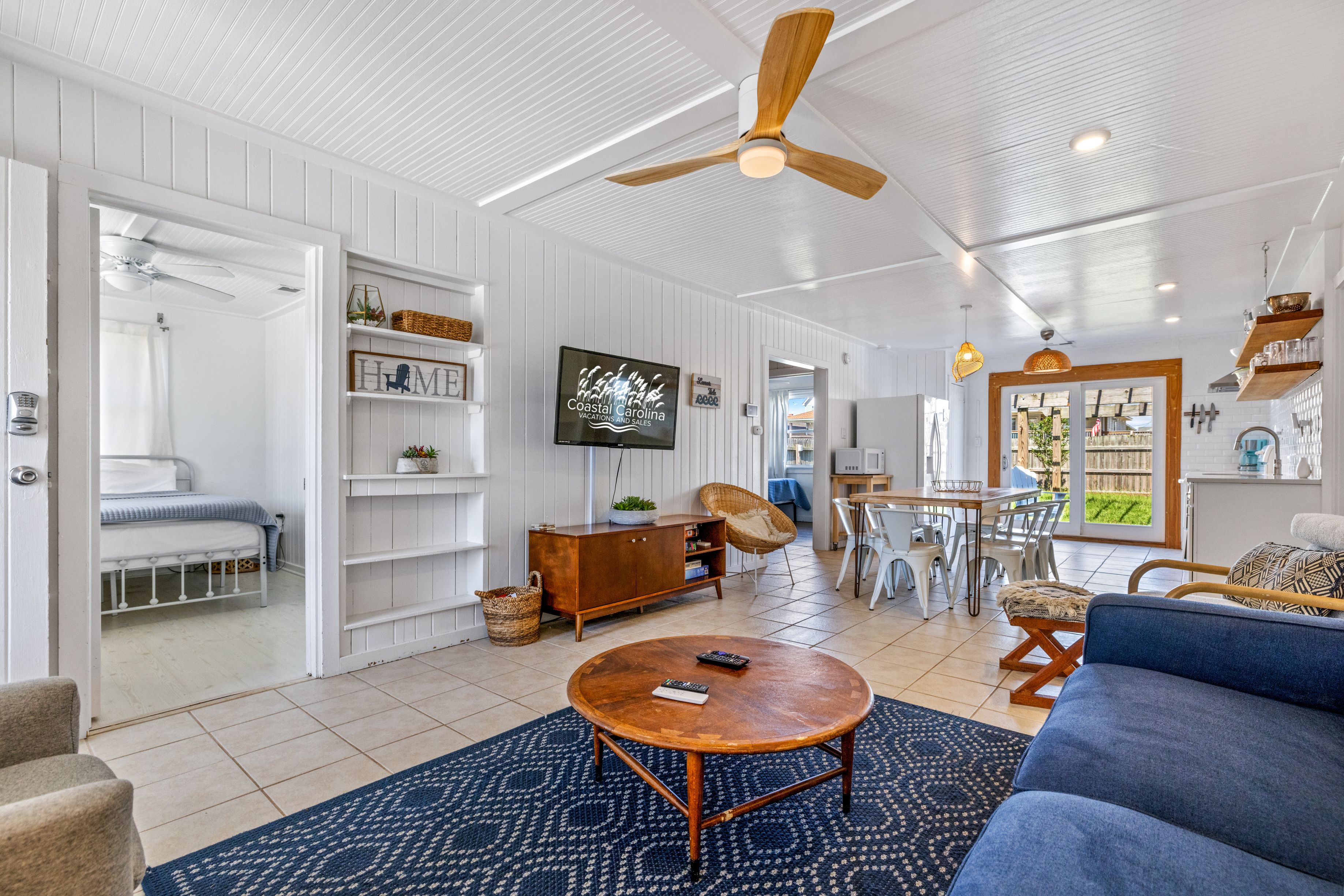 A spacious living room with a round wooden coffee table, a blue sofa, and a ceiling fan.