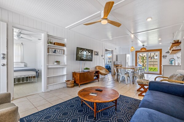 A spacious living room with a round wooden coffee table, a blue sofa, and a ceiling fan.