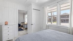 A bedroom with a bed, a dresser, and a window with a view of the outside. - Lunar Tide: Pet Friendly, Oceanside, Close to Beach and Avalon Pier (Kill Devil Hills)